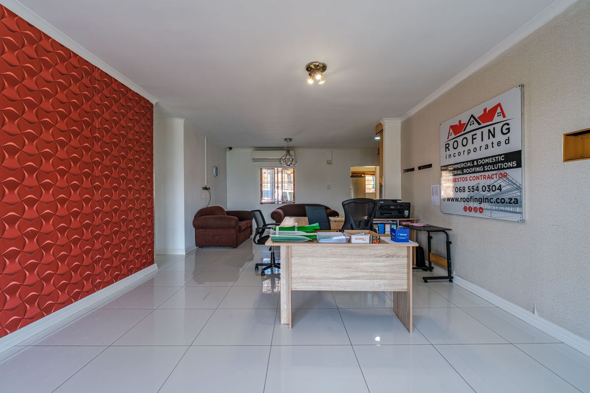 Spacious living area featuring polished tile flooring, a bold textured feature wall, and a wall-mounted air conditioning unit.