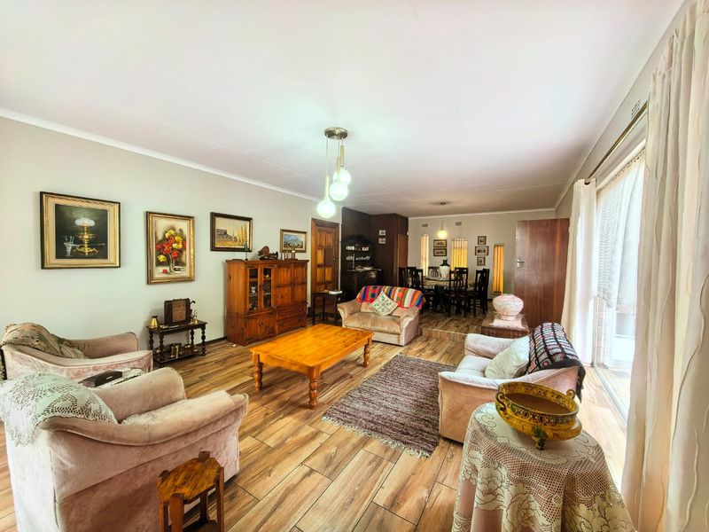 Spacious open-plan living and dining area featuring wood-look laminate flooring, pendant lighting, and a raised dining section with access to a sliding glass door.