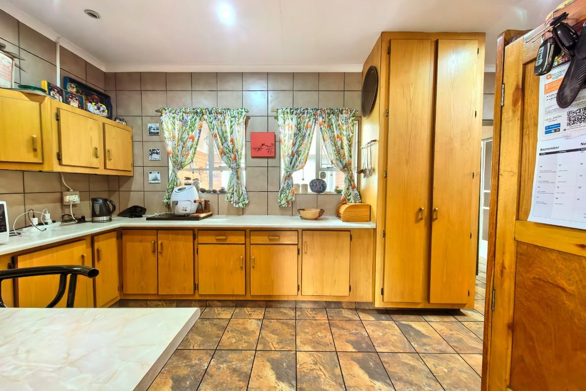 A functional kitchen featuring wooden cabinetry, tiled backsplash, and tiled flooring, offering ample storage space and a classic layout.