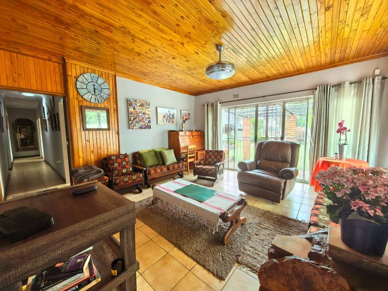 A living room featuring a warm timber-clad ceiling, tiled flooring, and large sliding glass doors that provide access to the outdoor area.