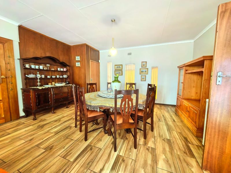 A dining room featuring wood-look tile flooring, built-in wood paneling, and a central pendant light fixture.