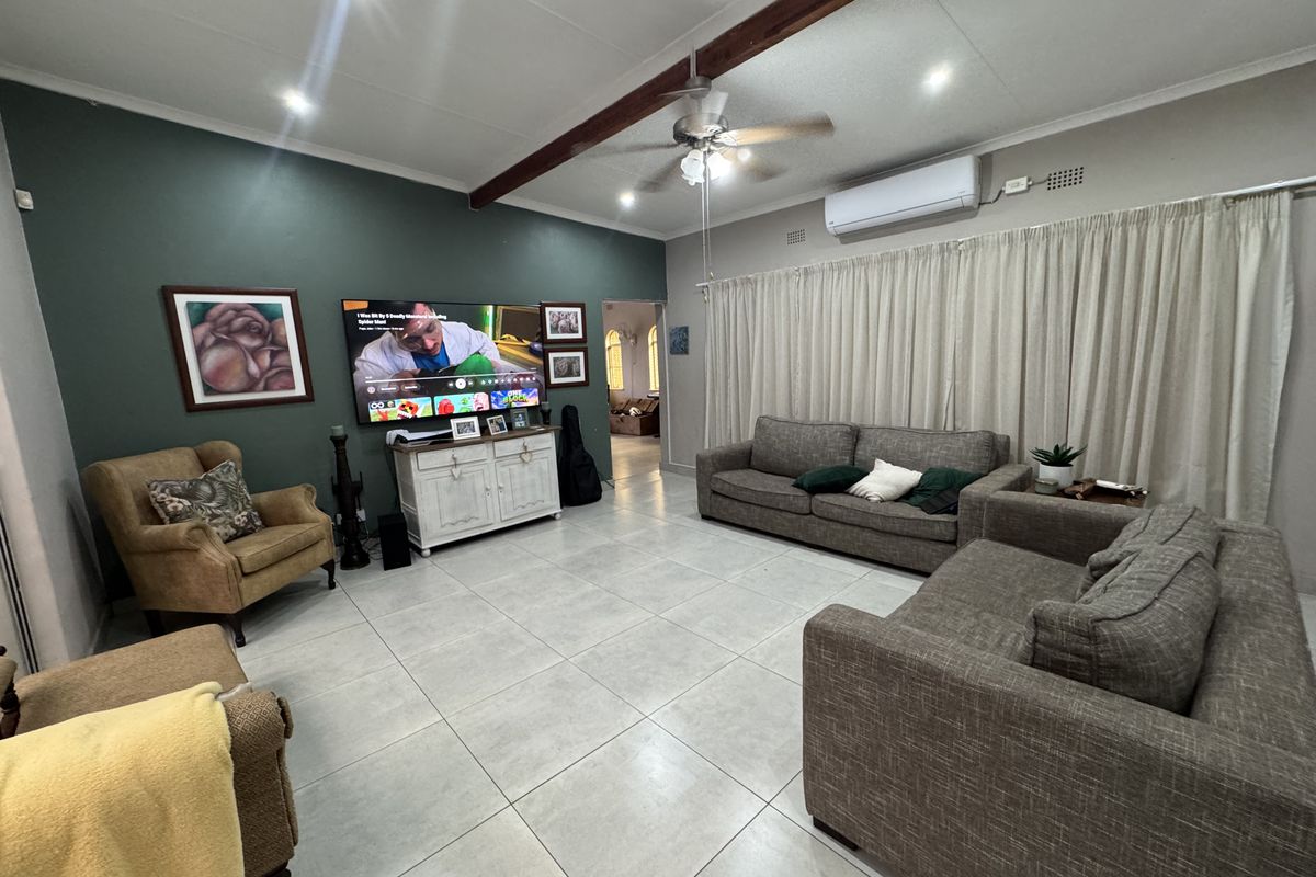 Spacious living room featuring tiled flooring, a ceiling fan, split-system air conditioning, and a decorative exposed timber ceiling beam.