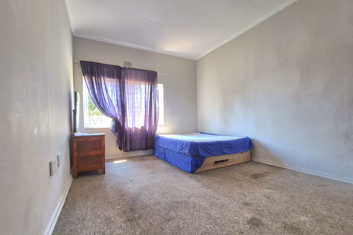 A bedroom featuring carpeted flooring and a window with natural light. The room requires cosmetic updates to the flooring and wall finishes.