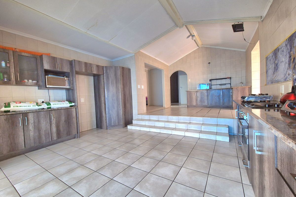 Spacious kitchen featuring tiled flooring, built-in cabinetry, a gas hob, and a raised platform area with an archway leading to adjacent rooms.