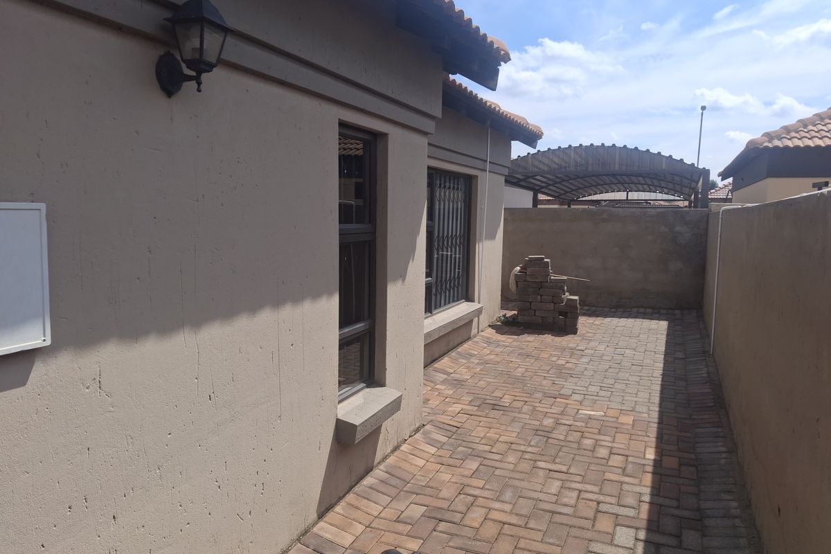 A paved rear courtyard area featuring perimeter walls, security gates, and exterior lighting, providing a functional outdoor space.