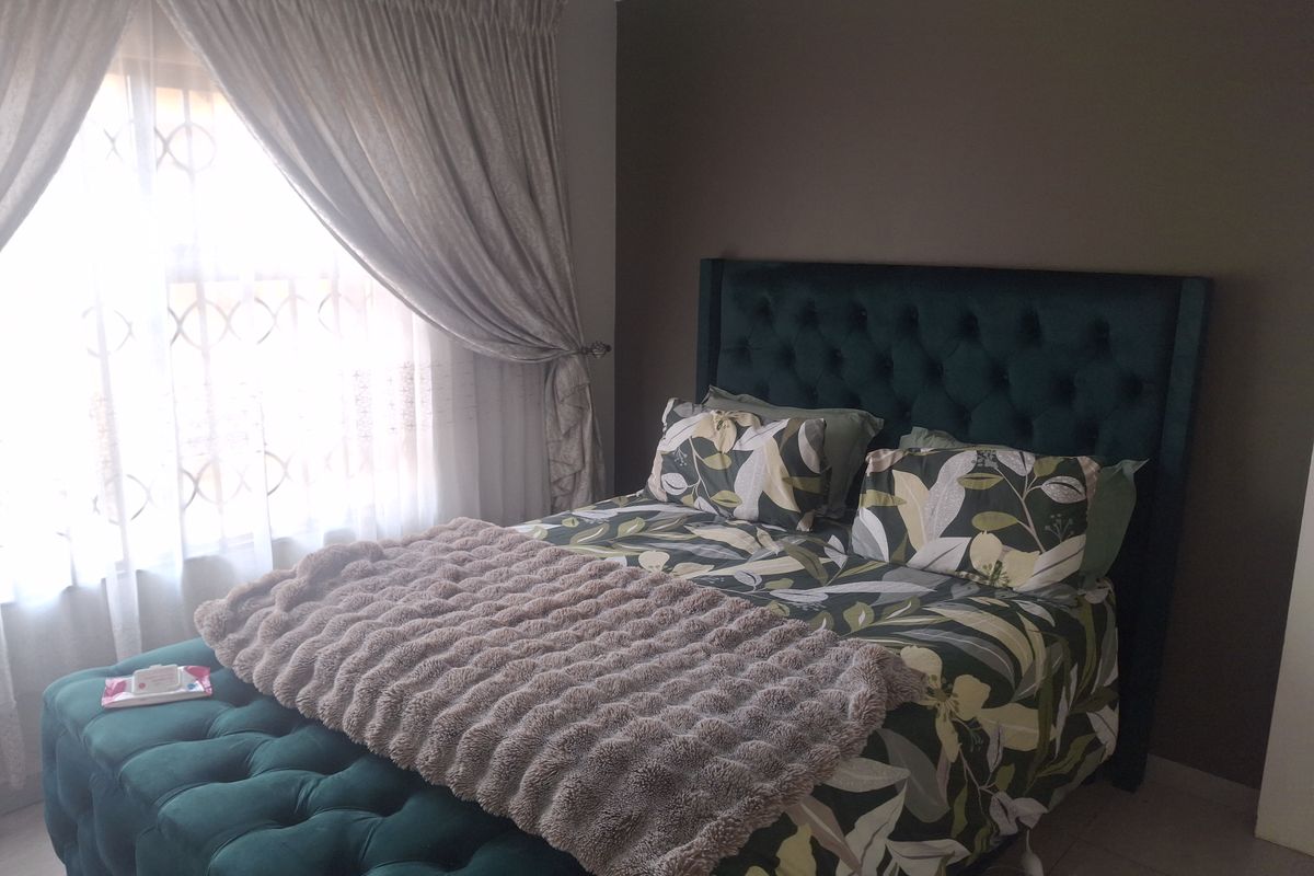 A well-maintained bedroom featuring neutral wall tones and natural light through window treatments.