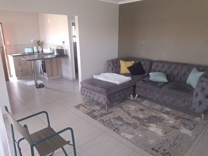 Open plan living area featuring tiled flooring and a functional kitchen with built-in cabinetry and a breakfast bar.