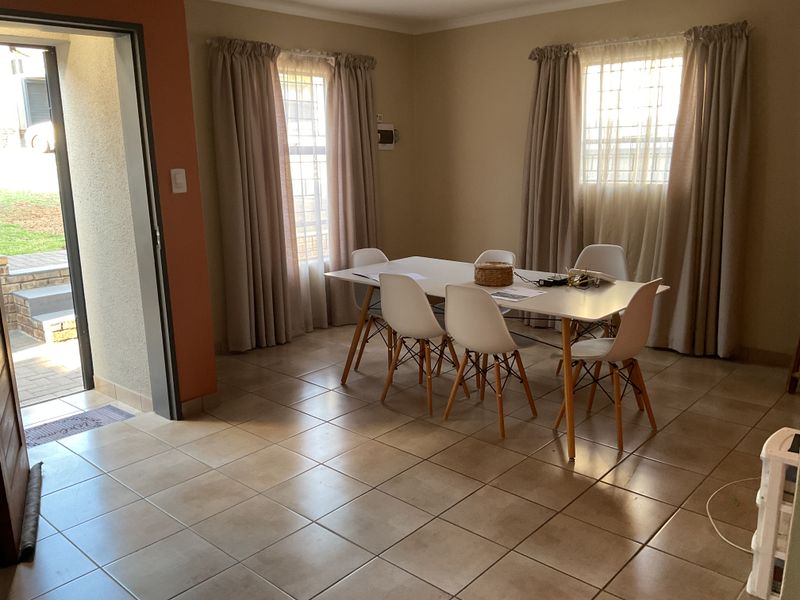 Dining room featuring tiled flooring and natural light through windows with security bars, providing direct access to the exterior.