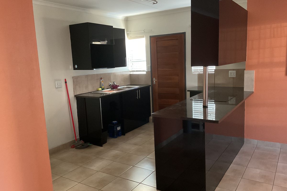 A functional kitchen featuring dark cabinetry, granite countertops, a breakfast bar, and tiled flooring, providing a clean and practical workspace.