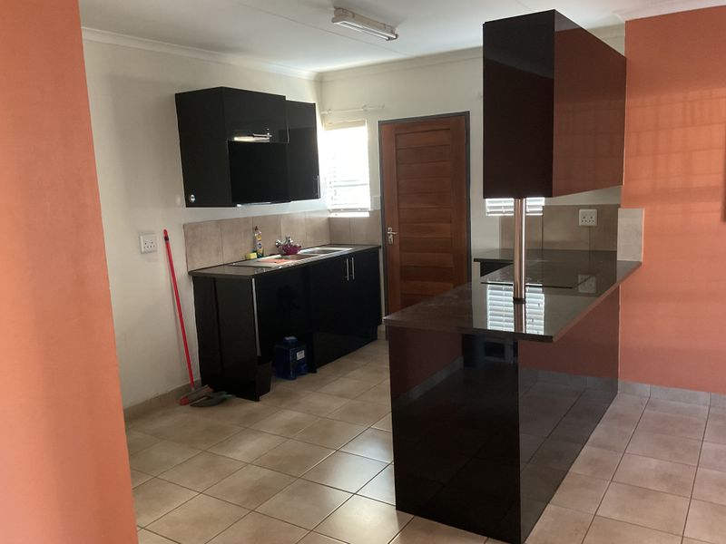 A functional kitchen featuring dark cabinetry, granite countertops, a breakfast bar, and tiled flooring, providing a clean and practical workspace.