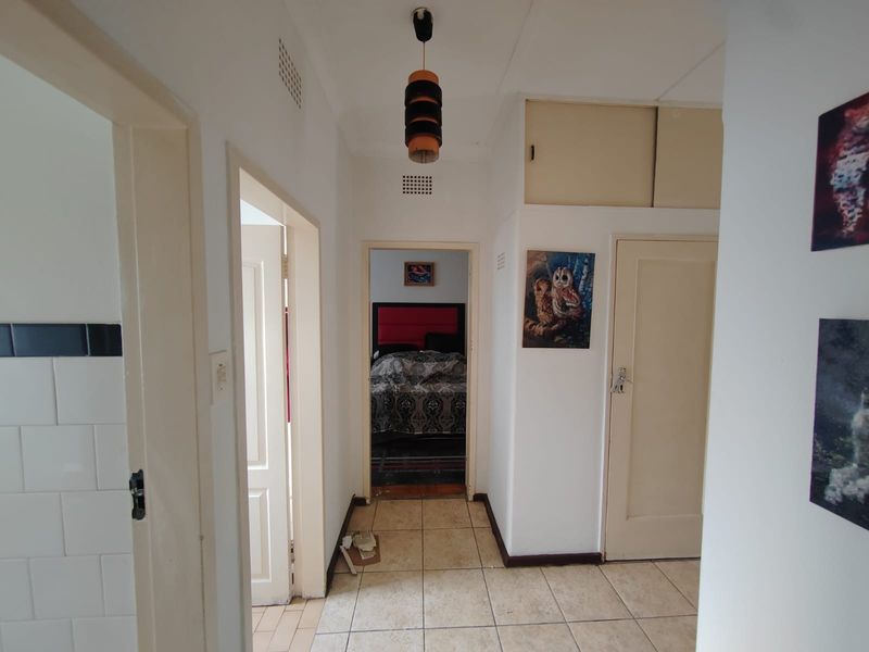A functional hallway featuring tiled flooring, built-in storage cabinetry, and access to adjacent rooms.