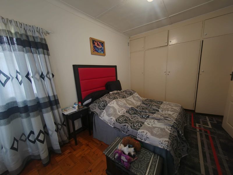 A bedroom featuring classic parquet flooring and extensive built-in cupboard storage, offering a functional and traditional layout.