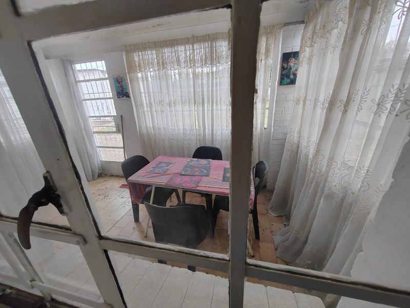 Enclosed patio area featuring tiled flooring and painted brick walls, viewed through a window frame.