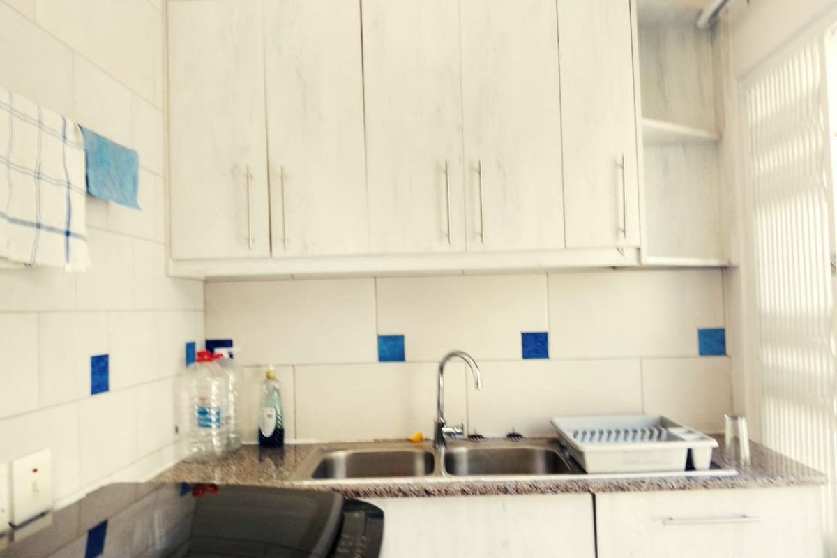A functional kitchen area featuring white cabinetry, granite countertops, a double bowl stainless steel sink, and a tiled splashback.