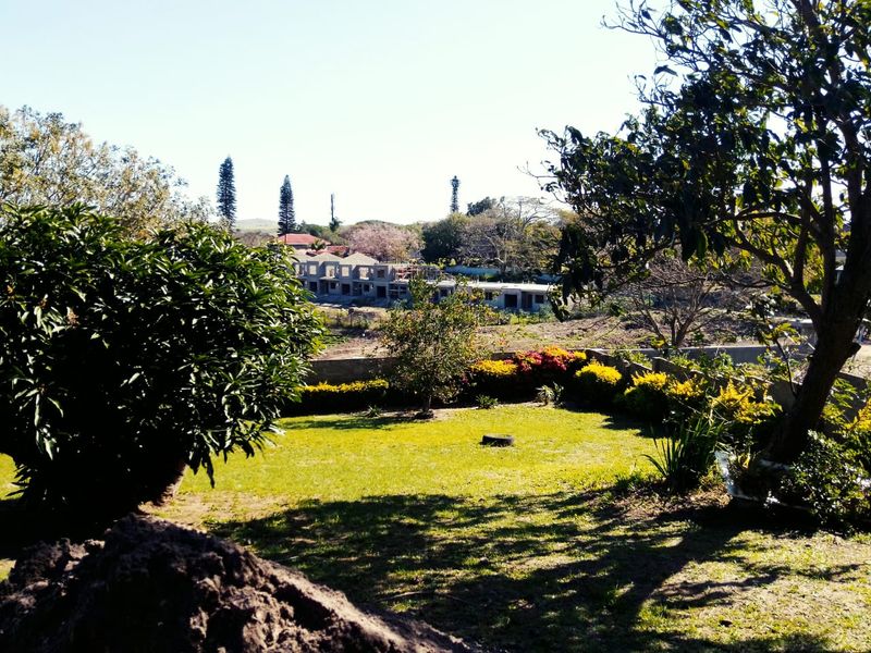 A spacious residential garden featuring a well-maintained lawn, mature trees, and established shrubbery, offering a pleasant outdoor space with views of the surrounding area.