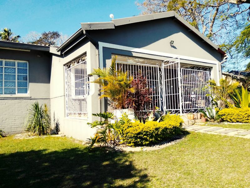 A view of the rear exterior of the house featuring security gates and bars on the windows and doors, set within a landscaped garden.