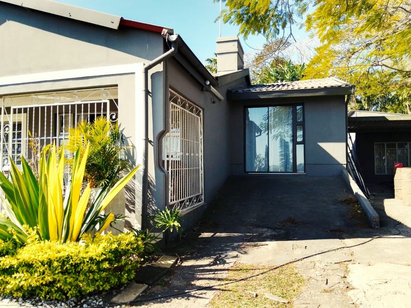 Front exterior view of the house featuring a concrete driveway, security bars on windows, and a chimney stack.