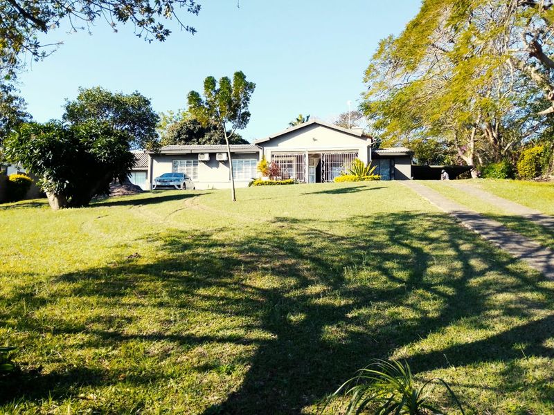 Front view of a single-story residential house featuring a large front lawn, concrete driveway, and security bars on windows.