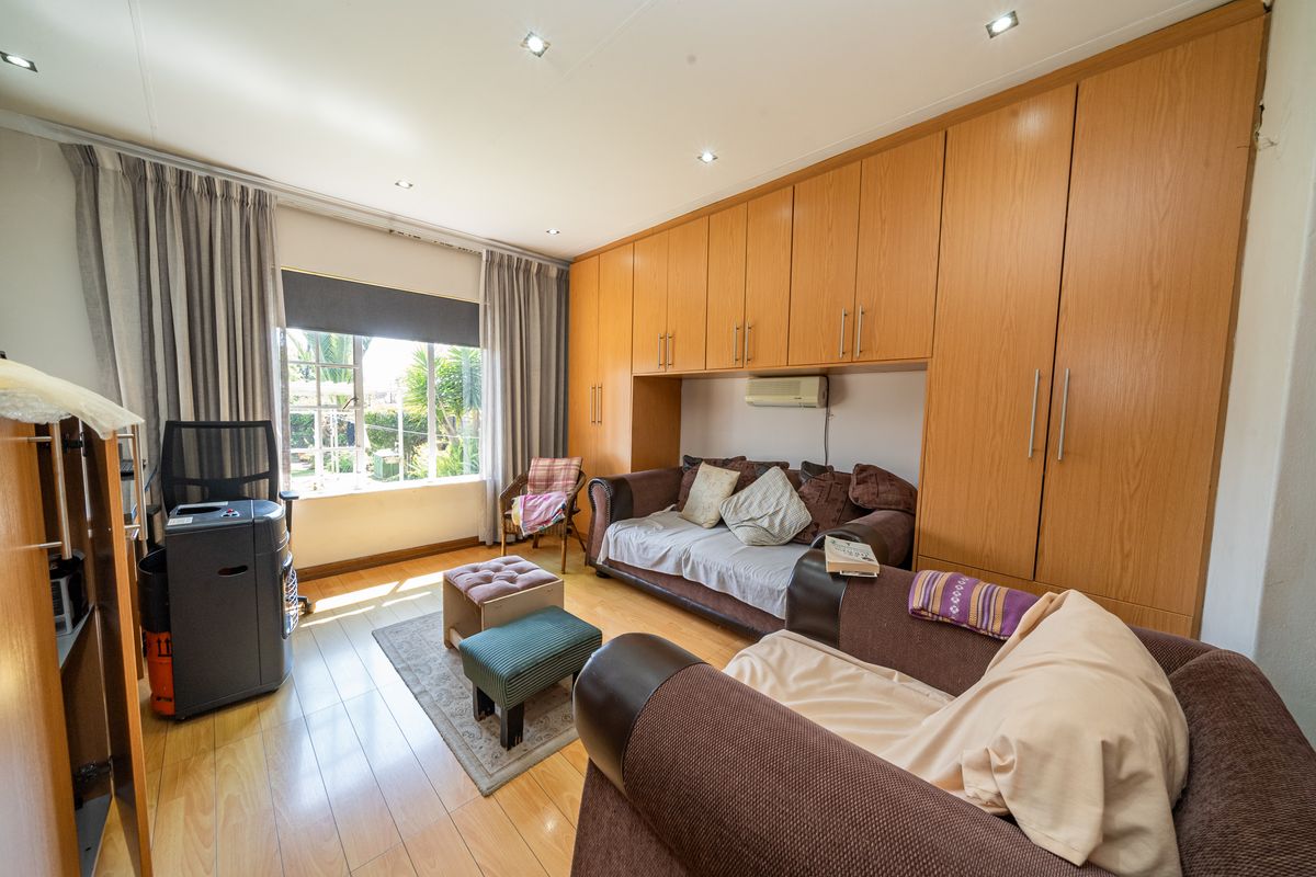 A bedroom featuring extensive built-in wooden cabinetry, laminate flooring, recessed lighting, and an integrated air conditioning unit.