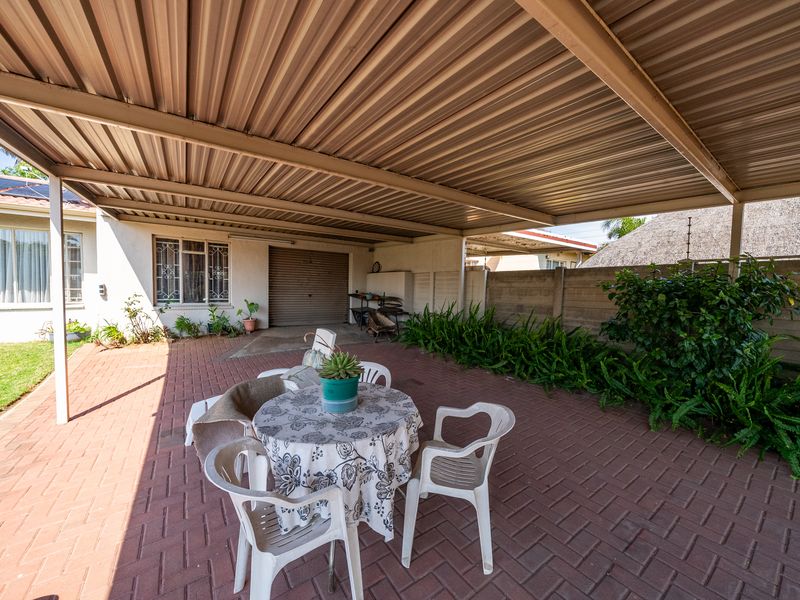 A covered outdoor patio area featuring paved flooring and a corrugated metal roof, providing a functional space for outdoor relaxation.