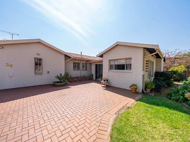 Front exterior view of the house featuring a brick paved driveway, tiled roof, and established garden area.