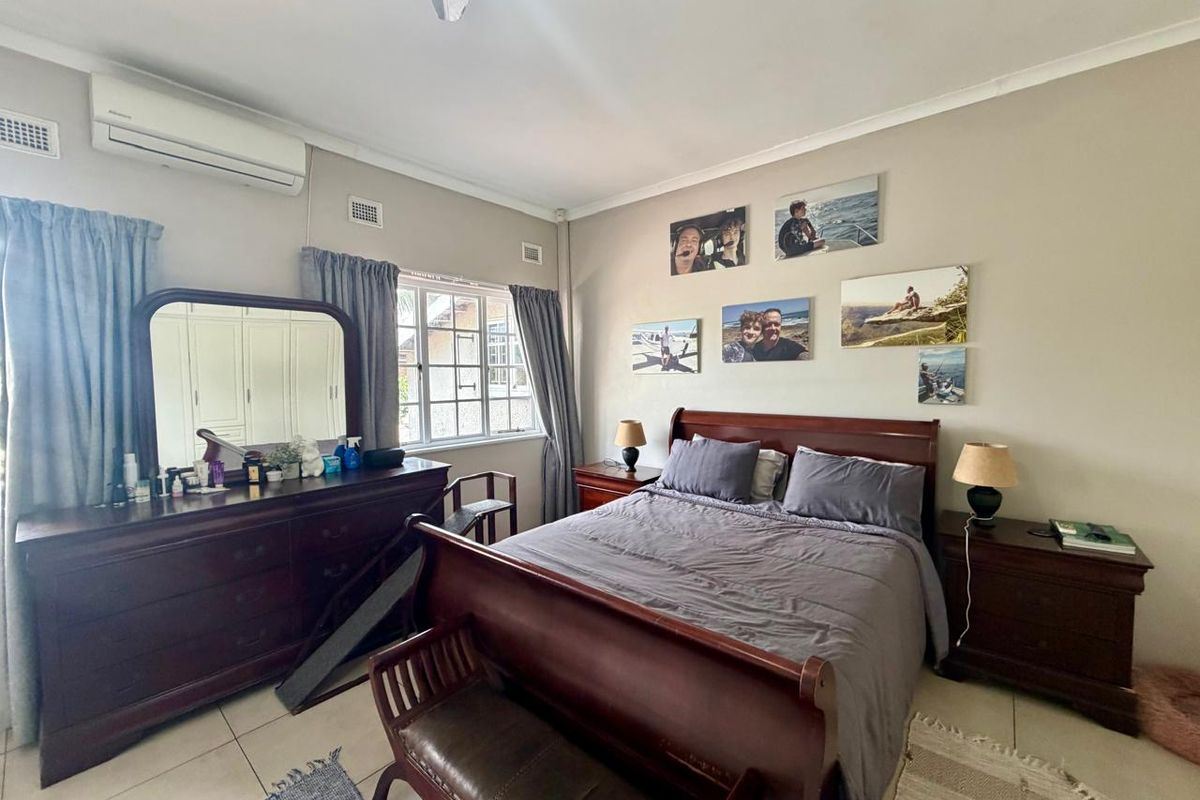 A well-lit bedroom featuring tiled flooring, built-in cupboards, and a wall-mounted split-system air conditioner.
