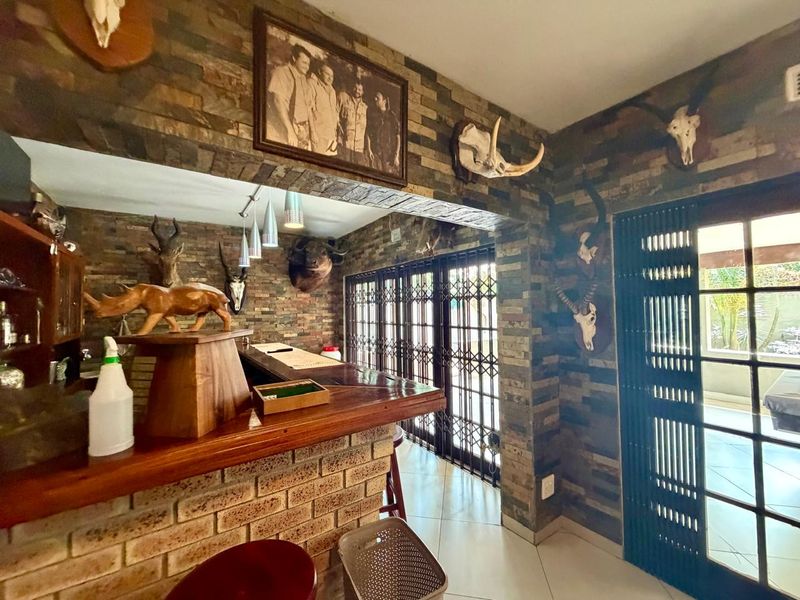 A dedicated bar area featuring brick-clad walls, a built-in bar counter, and security gates leading to the outdoor space.