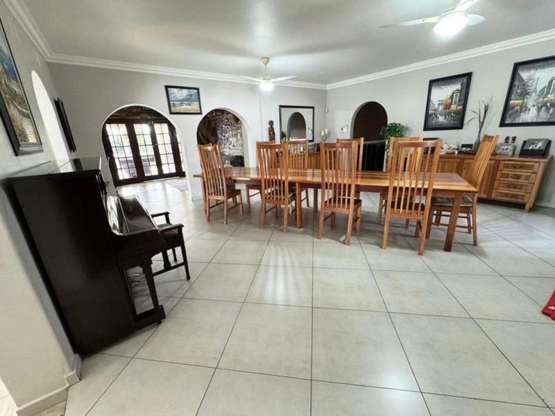 Spacious dining area featuring large format floor tiles, decorative archways, and ceiling fans, providing a bright and open space for formal entertaining.