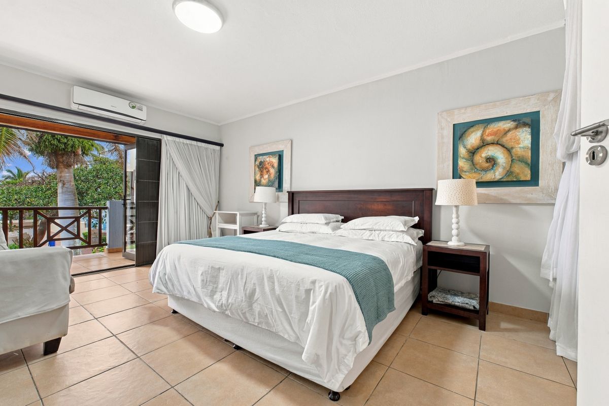 Spacious bedroom featuring tiled flooring, air conditioning, and direct access to a private balcony through large sliding glass doors.