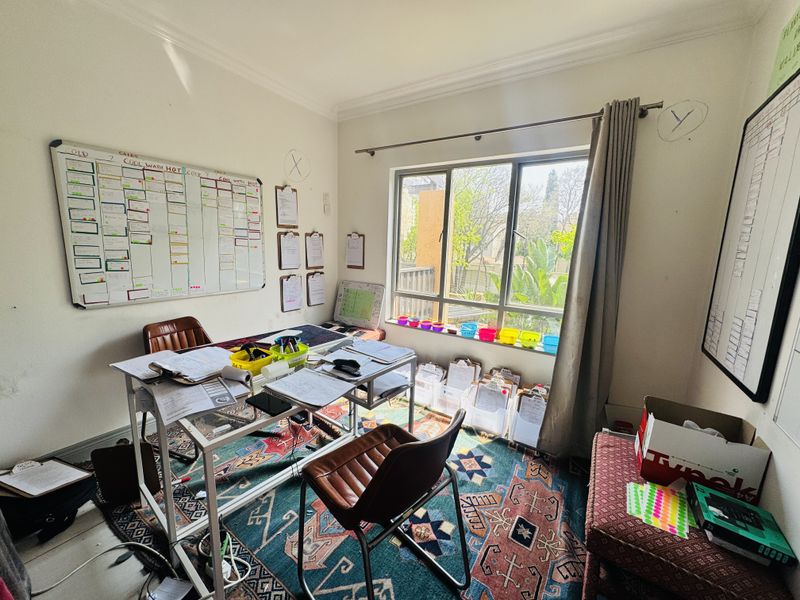 A functional home office space featuring a large window with natural light, neutral walls, and classic coving detail.