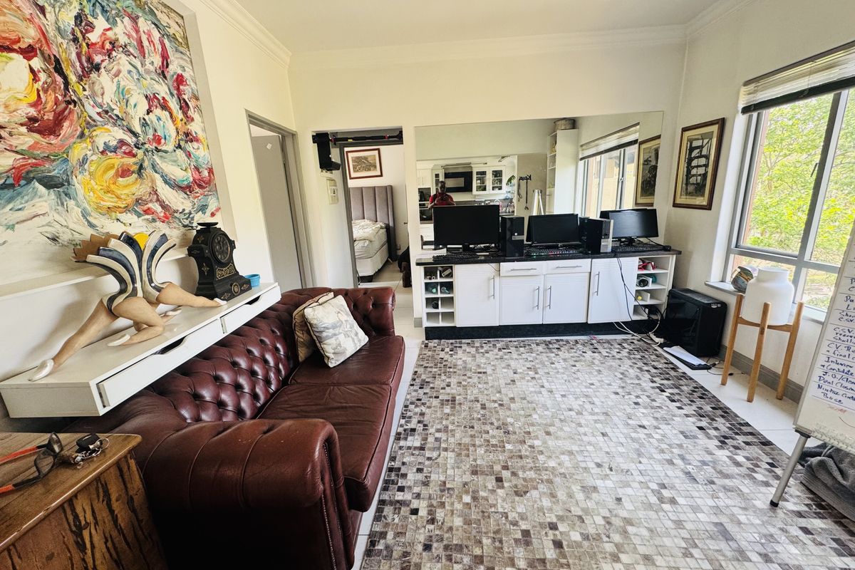 A living room featuring tiled flooring, built-in cabinetry with a large wall mirror, and natural light from a large window.