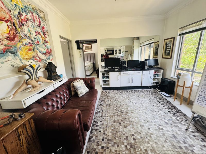 A living room featuring tiled flooring, built-in cabinetry with a large wall mirror, and natural light from a large window.
