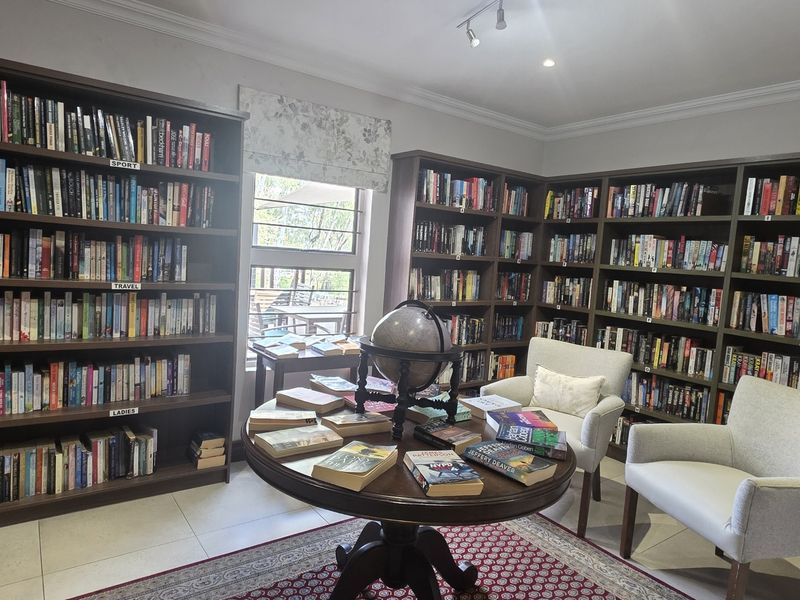 A well-maintained home library or study featuring extensive built-in floor-to-ceiling shelving, tiled flooring, and recessed lighting.