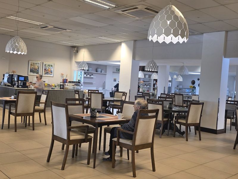 Spacious open-plan dining and communal area featuring ceramic tiled flooring, suspended ceilings with integrated lighting, and a built-in service counter.