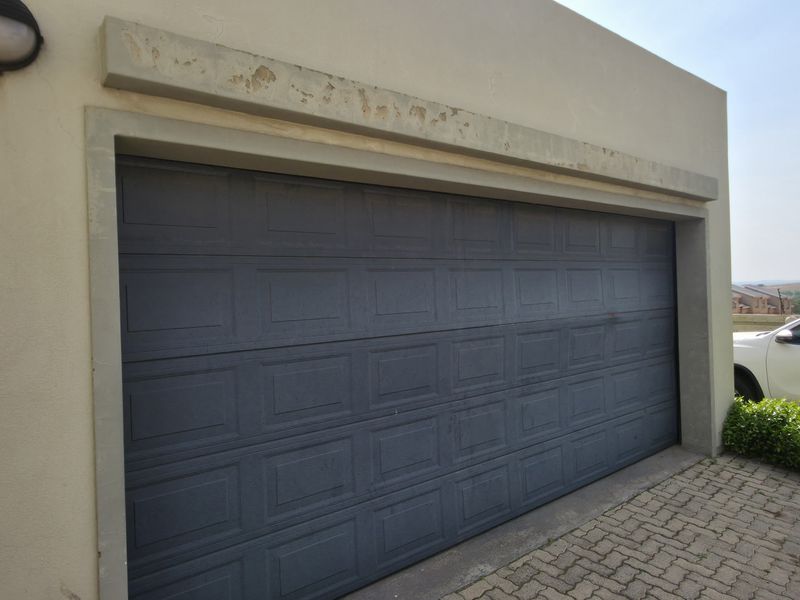 Exterior view of a residential garage featuring a dark sectional door and paved driveway access.