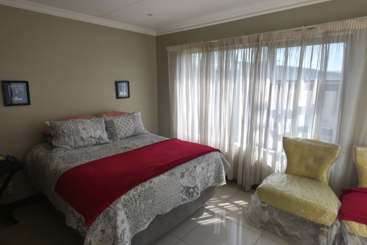 A well-maintained bedroom featuring tiled flooring, cove cornicing, and recessed downlights, offering a neutral and functional living space.