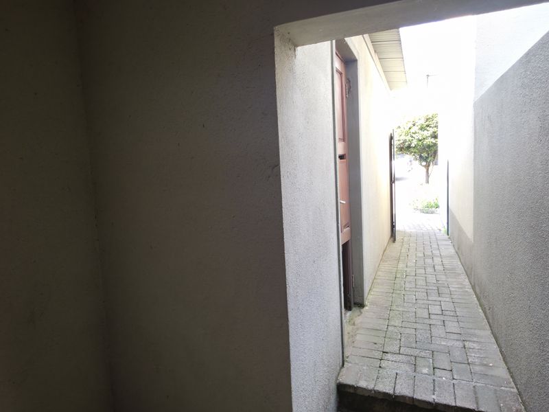 A narrow paved side passage or walkway leading to the rear exterior area of the townhouse.