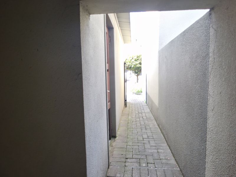 A narrow paved side passage or walkway leading to the rear garden area of the townhouse.