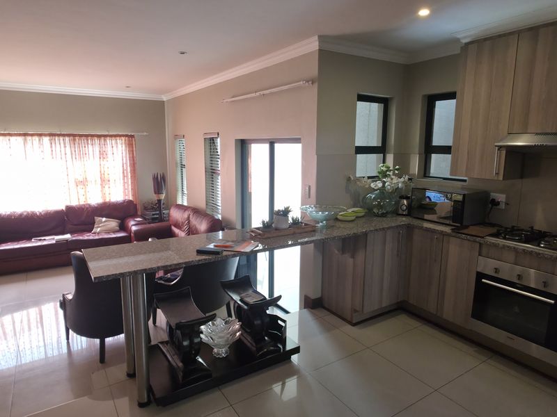 Open-plan living area featuring a modern kitchen with granite countertops, built-in oven, gas hob, and a breakfast bar flowing into the lounge space.