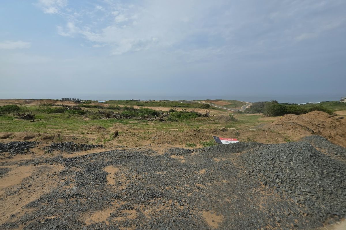 A wide-angle view of an undeveloped residential plot featuring natural coastal terrain and distant ocean views.