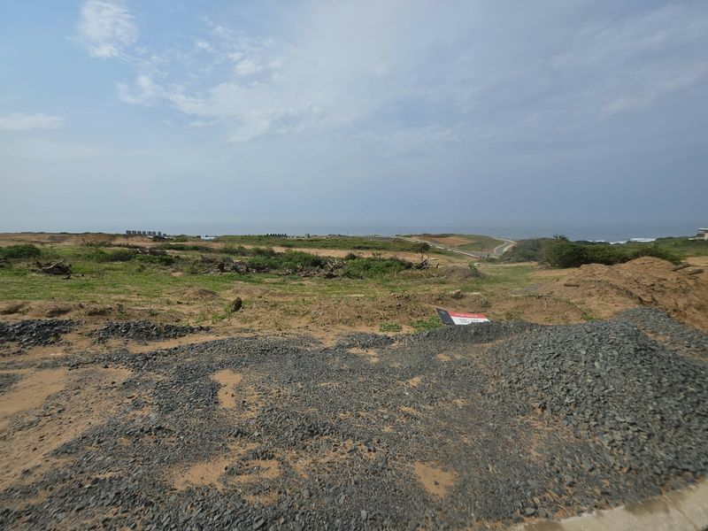 A wide-angle view of an undeveloped residential plot featuring natural coastal terrain and distant ocean views.