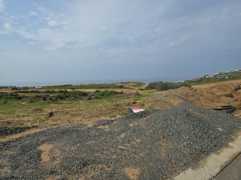 A vacant residential plot of land featuring coastal views and natural terrain, ready for development in a scenic estate setting.