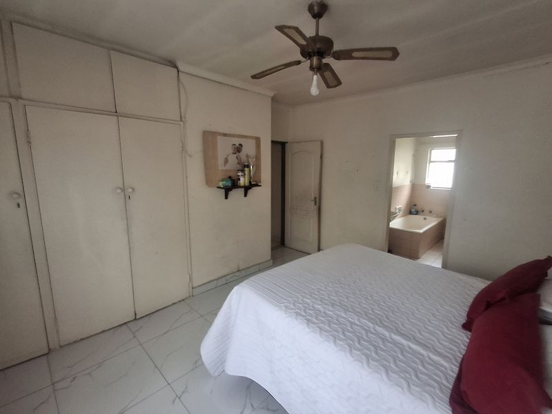 Bedroom featuring built-in cupboards, tiled flooring, a ceiling fan, and an adjoining en-suite bathroom.