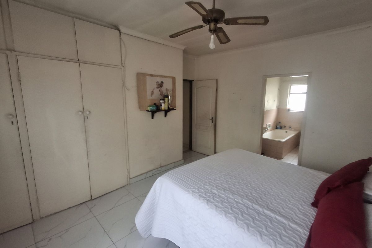 Bedroom featuring built-in cupboards, tiled flooring, a ceiling fan, and an adjoining en-suite bathroom.
