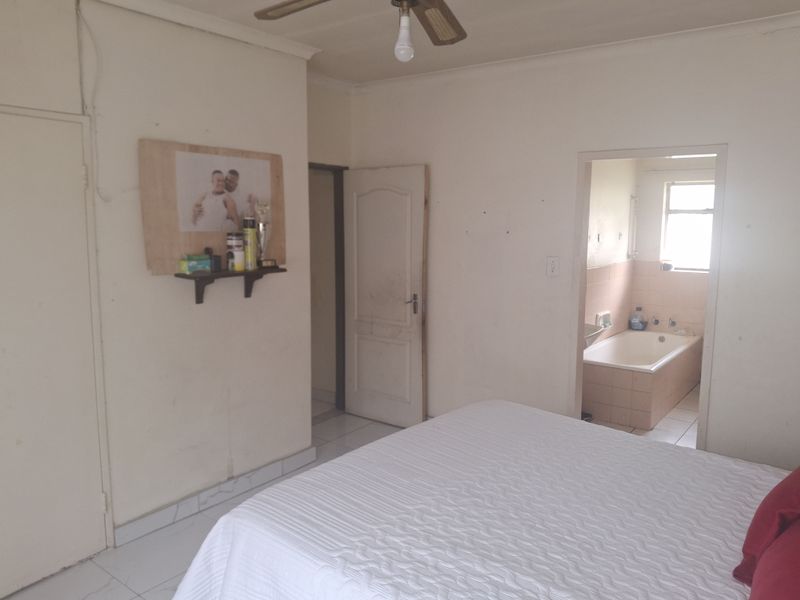 Bedroom featuring tiled flooring, a ceiling fan, and an adjoining en-suite bathroom with a built-in bathtub.
