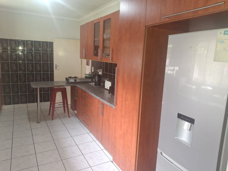 A functional kitchen featuring wood-finish cabinetry, tiled backsplash, and a breakfast bar, providing a practical workspace with standard finishes.
