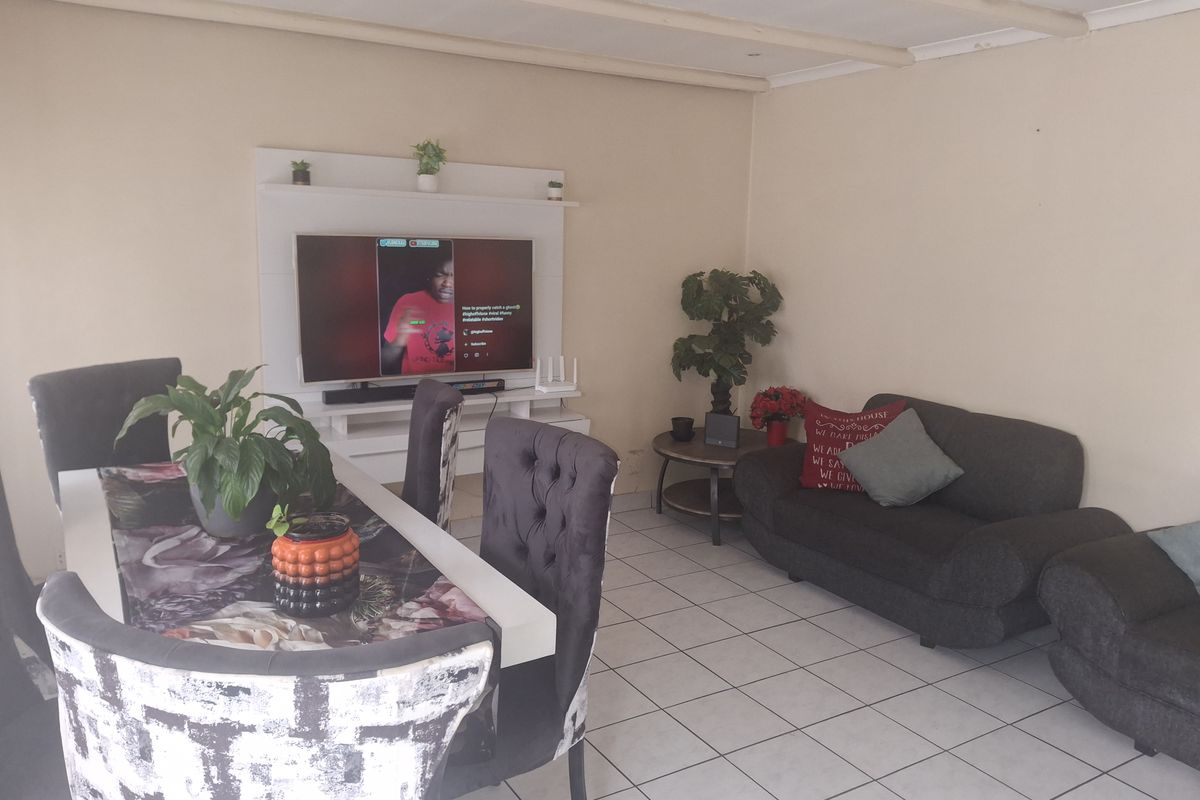 A living room featuring tiled flooring, exposed ceiling beams, and a built-in media unit, offering a functional space for relaxation and entertainment.