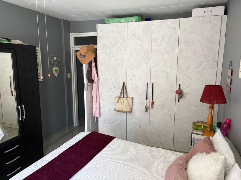 A bedroom featuring grey walls, tiled flooring, and a large built-in wardrobe with a marble-effect finish.