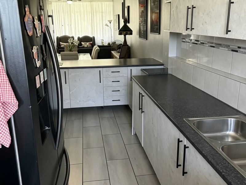 Open plan kitchen and living area featuring modern laminate cabinetry, dark countertops, tiled flooring, and dual ceiling fans.
