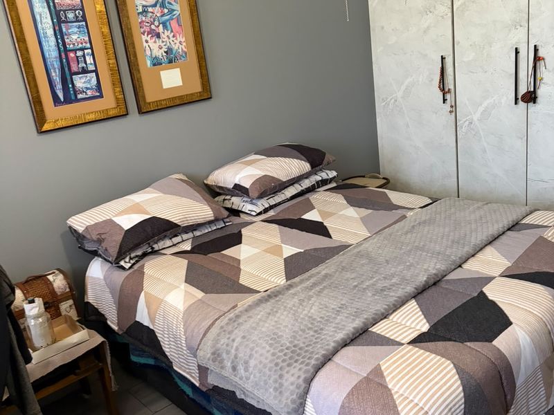 A bedroom featuring a built-in wardrobe with a marble-effect finish and grey painted walls.
